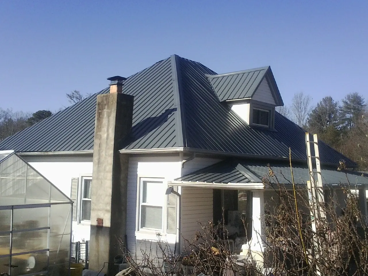 Dark blue standing seam metal roof on a white farmhouse with dormer — Slate & Tile Roof Repair by Roofing Brothers in Fairfax